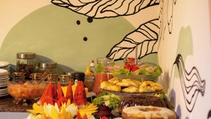 A buffet with various food items and a decorative wall in the background. - Pousada Pura Vida (Itacaré)
