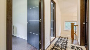 A hallway with a dark wooden door, a white wall, and a patterned rug. - Room-double Room 2 Brampton Toronto Cana (Brampton)
