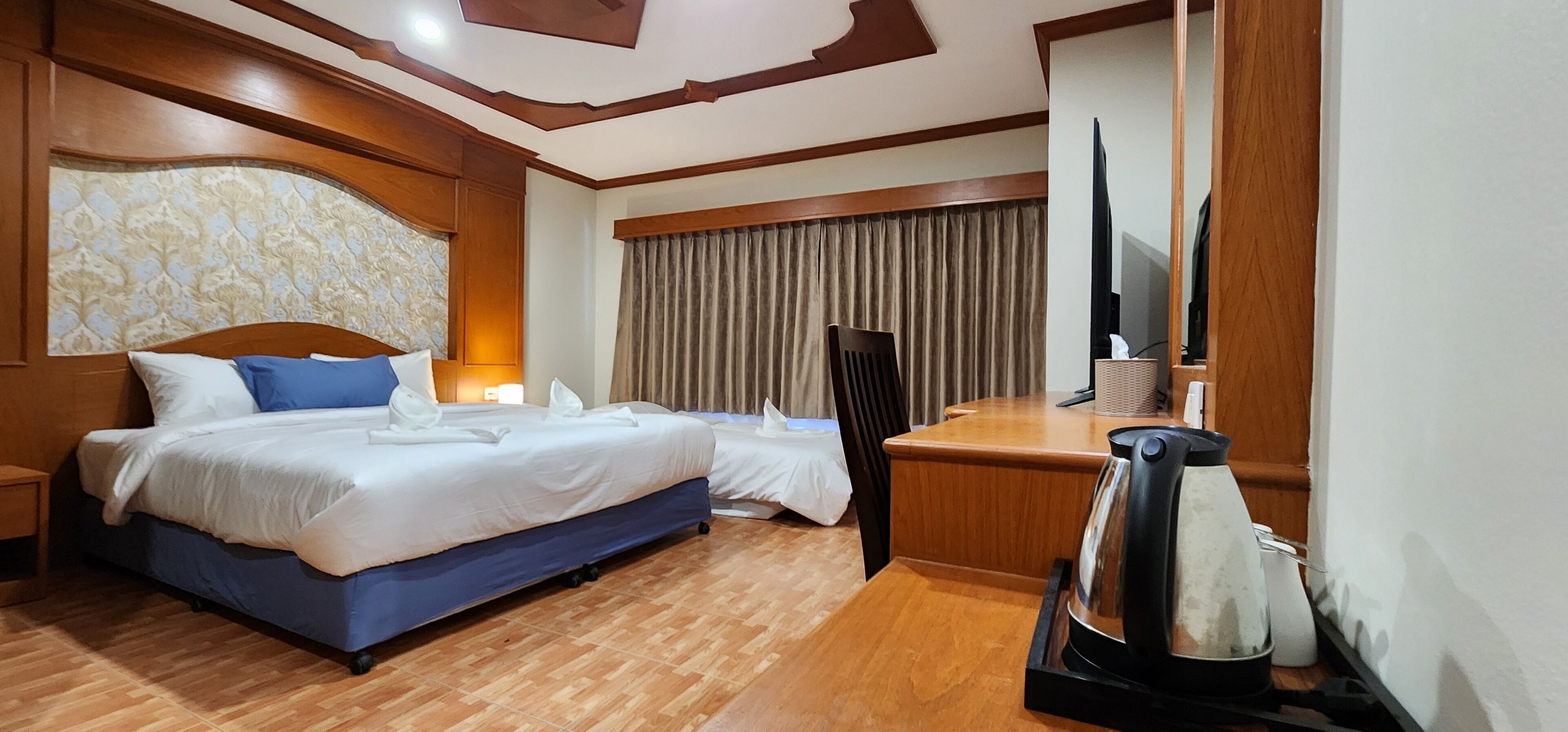 A hotel room with a large bed, a desk, a chair, a television, and a coffee maker.