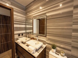 Un baño moderno con dos lavamanos, un espejo grande y una planta en maceta.