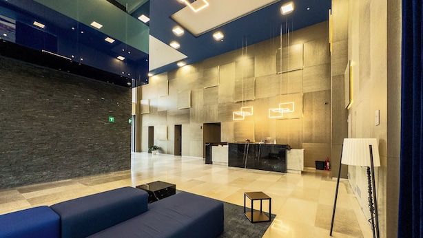 A modern lobby with a reception desk, seating area, and geometric light fixtures. - Apartamento con Alberca y Padel (Mexico City)
