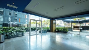 A spacious lobby with a glass entrance, potted plants, and a modern architectural design. - Apartamento con Alberca y Padel (Mexico City)