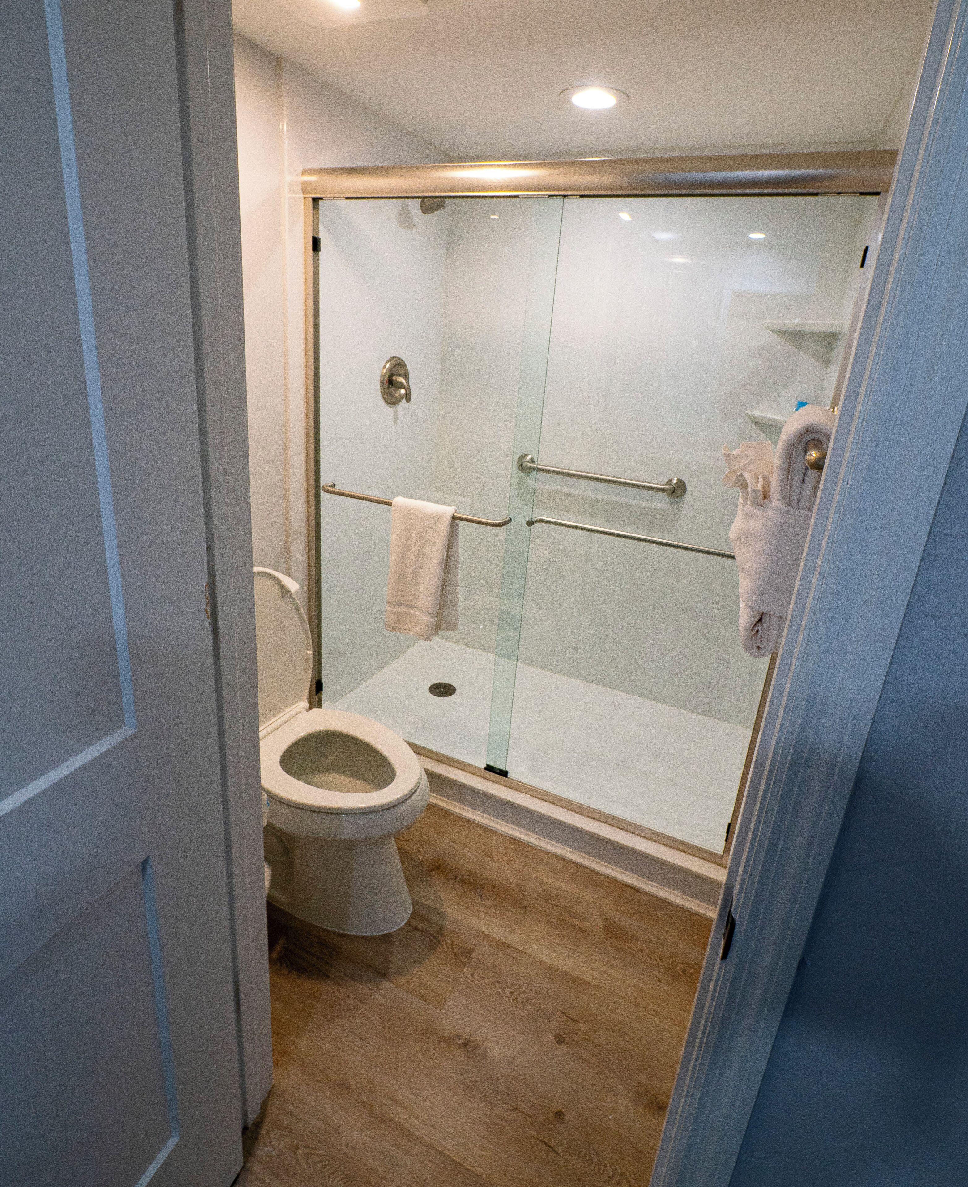 A modern bathroom with a glass-enclosed shower, a toilet, and a towel rack.
