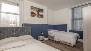 Ein Schlafzimmer mit zwei Betten, einem Nachttisch, einem Bild und einem Fenster mit Jalousien.