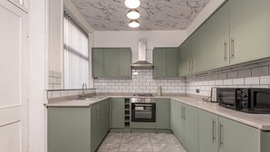 Eine Küche mit grünen Schränken, einem eingebauten Backofen, einer Mikrowelle und einem Gasherd.