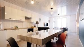 A modern kitchen with a central island, white cabinetry, and a dining area with chairs. - Le reflet des Pyrénées 6/8 people, close to town center and ski shuttles (Bagnères-de-Bigorre)