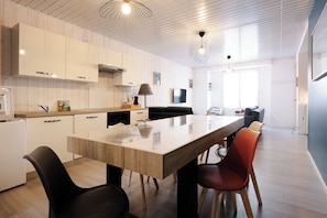 A modern kitchen with a central island, white cabinetry, and a dining area with chairs.