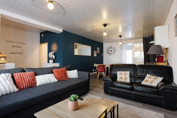 A modern living room with a dark grey sofa, a black leather sofa, and a wooden coffee table.
