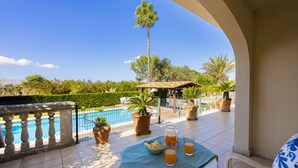 A terrace with a pool, potted plants, and a table with drinks and snacks. - Villa Can Emmes (Alcúdia)