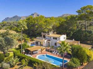 Une villa de style méditerranéen dotée d’une piscine, d’un espace salon extérieur et offrant une vue sur les collines environnantes.