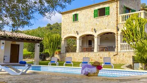 A stone building with a pool area, including lounge chairs and a covered seating area.