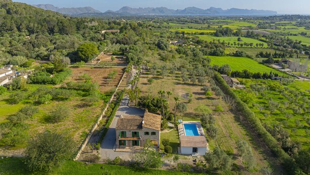 A rural property with a large house, a swimming pool, and expansive green fields.