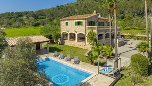 A stone villa with a swimming pool, outdoor seating, and a view of the surrounding countryside.