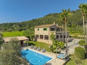 Une villa en pierre dotée d’une piscine, d’un espace extérieur aménagé et offrant une vue sur la campagne environnante.