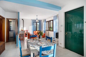Comedor con mesa lista para cuatro, sillas, candelabro y puerta verde.