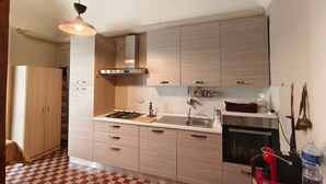 A modern kitchen with light wood cabinets, a gas stove, a sink, and a microwave. - RETROETNEA - Retro-style Apartment in historic center with 2 connecting bedrooms (Catania)