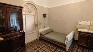 A small, compact room with a single bed, a wooden cabinet, and a patterned floor. - RETROETNEA - Retro-style Apartment in historic center with 2 connecting bedrooms (Catania)