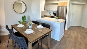 Une cuisine moderne avec des meubles blancs, un réfrigérateur en acier inoxydable et un îlot central.