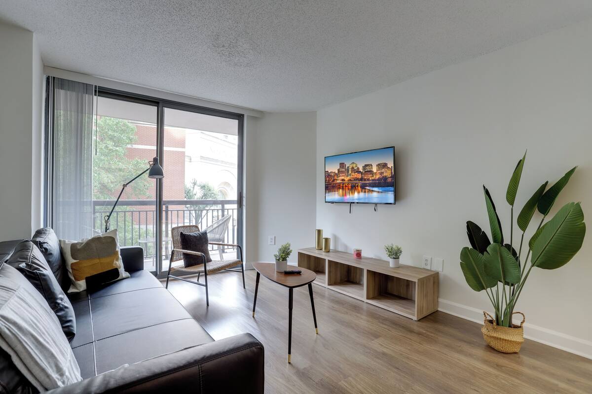 A modern living room with a sofa, a small table, and a large window.