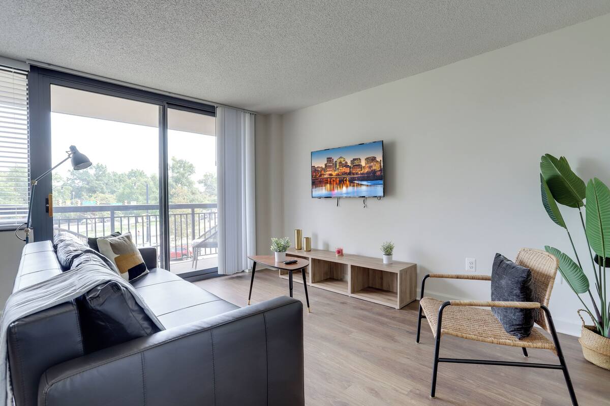 A modern living room with a sofa, a chair, a small table, and a TV mounted on the wall.