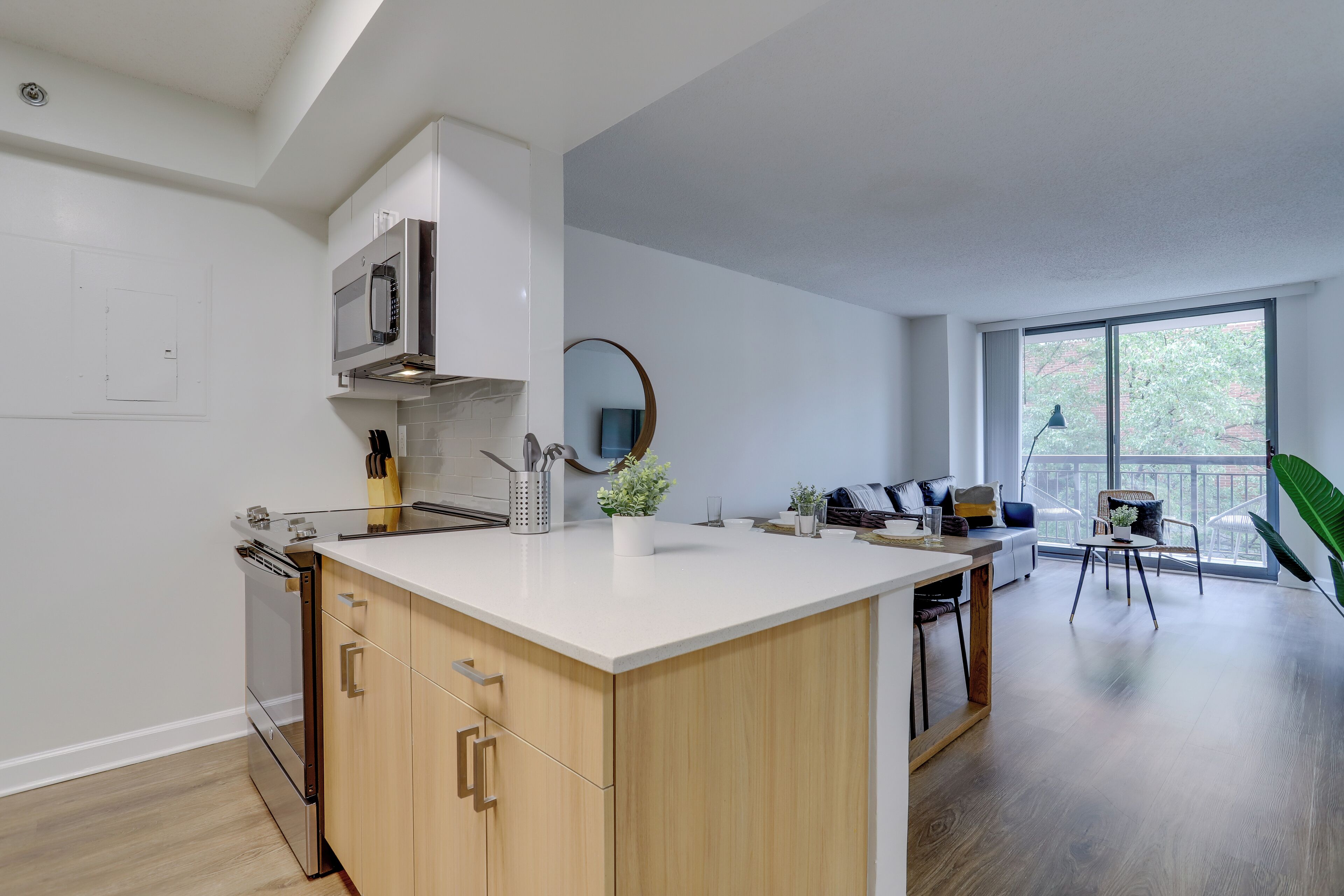 A modern kitchen with a central island, built-in appliances, and a dining area with a view.