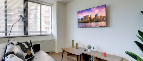 Een moderne woonkamer met een bank, een tafel, een lamp en een stadsgezichtschilderij aan de muur.
