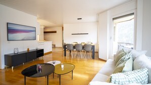 Ein modernes Wohnzimmer mit Essbereich, einer Couch und einem Fernseher.
