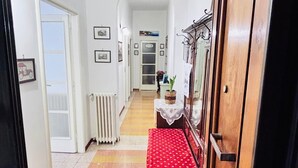 Un couloir avec un banc en bois, un radiateur et des tableaux encadrés accrochés aux murs.
