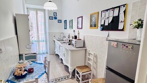 Une cuisine avec des meubles blancs, un réfrigérateur et un coin repas comprenant des chaises et une table.