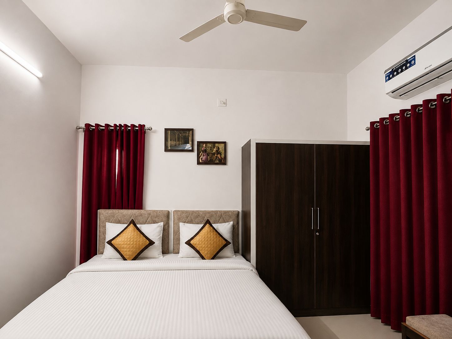 A bedroom with a bed, a wardrobe, a ceiling fan, and red curtains.
