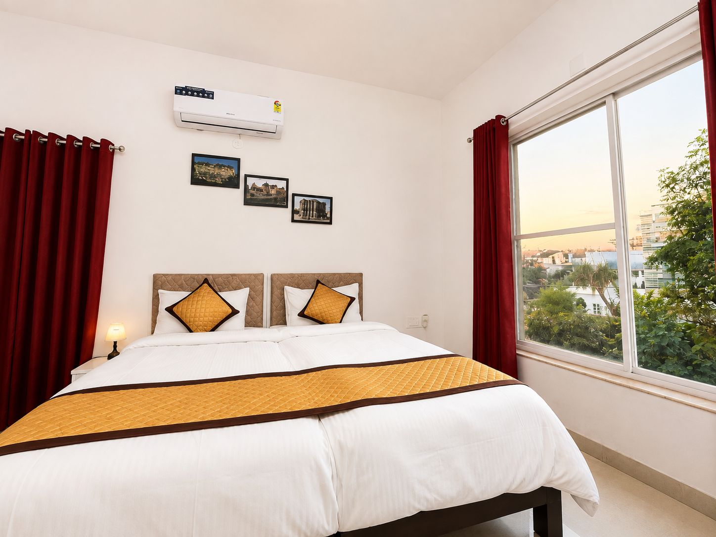 Une chambre d’hôtel avec un lit, des rideaux rouges, une fenêtre donnant sur un paysage agréable et un appareil de climatisation.