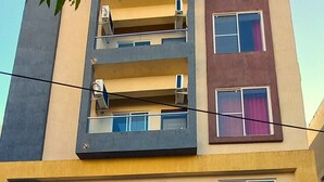 Un edificio residencial de varios pisos con balcones, ventanas grandes y una línea eléctrica visible.