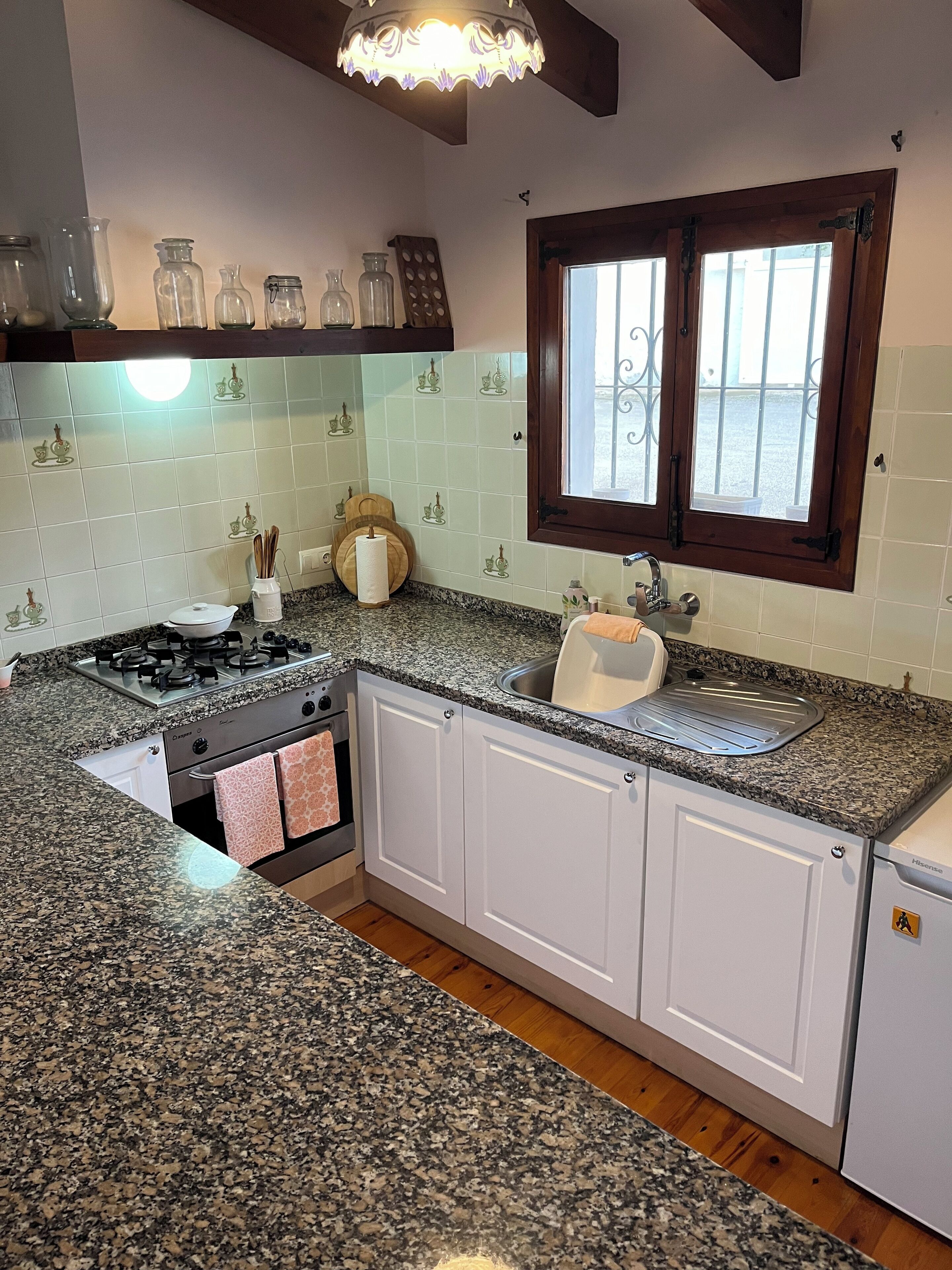 A kitchen with granite countertops, white cabinets, a stainless steel sink, and a window with a view.