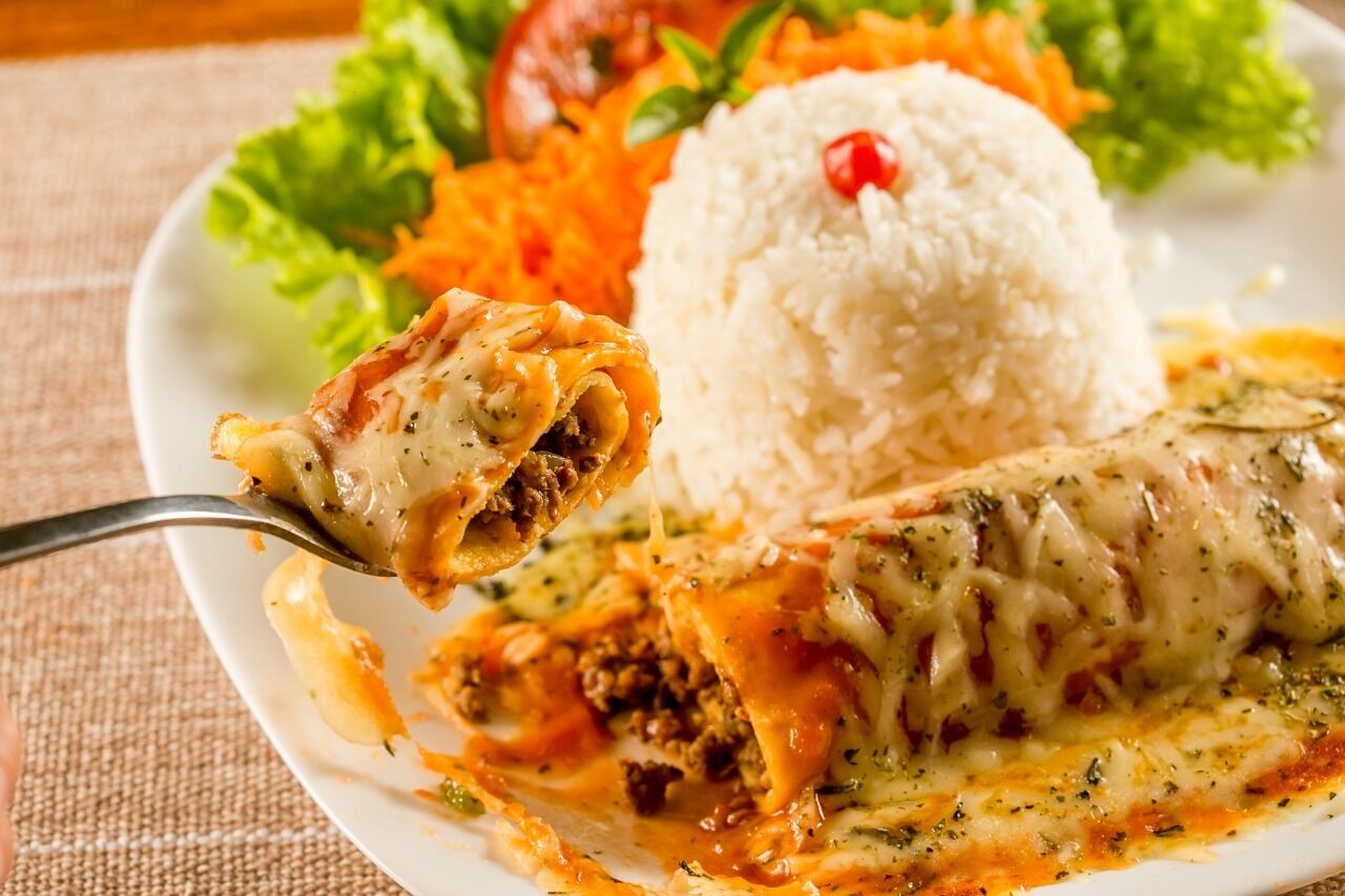 A plate with a rolled meat dish, rice, and vegetables.