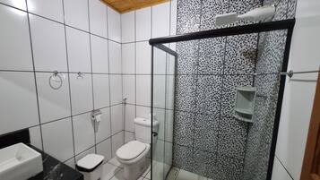 Baño con inodoro, bidé y cabina de ducha de vidrio.