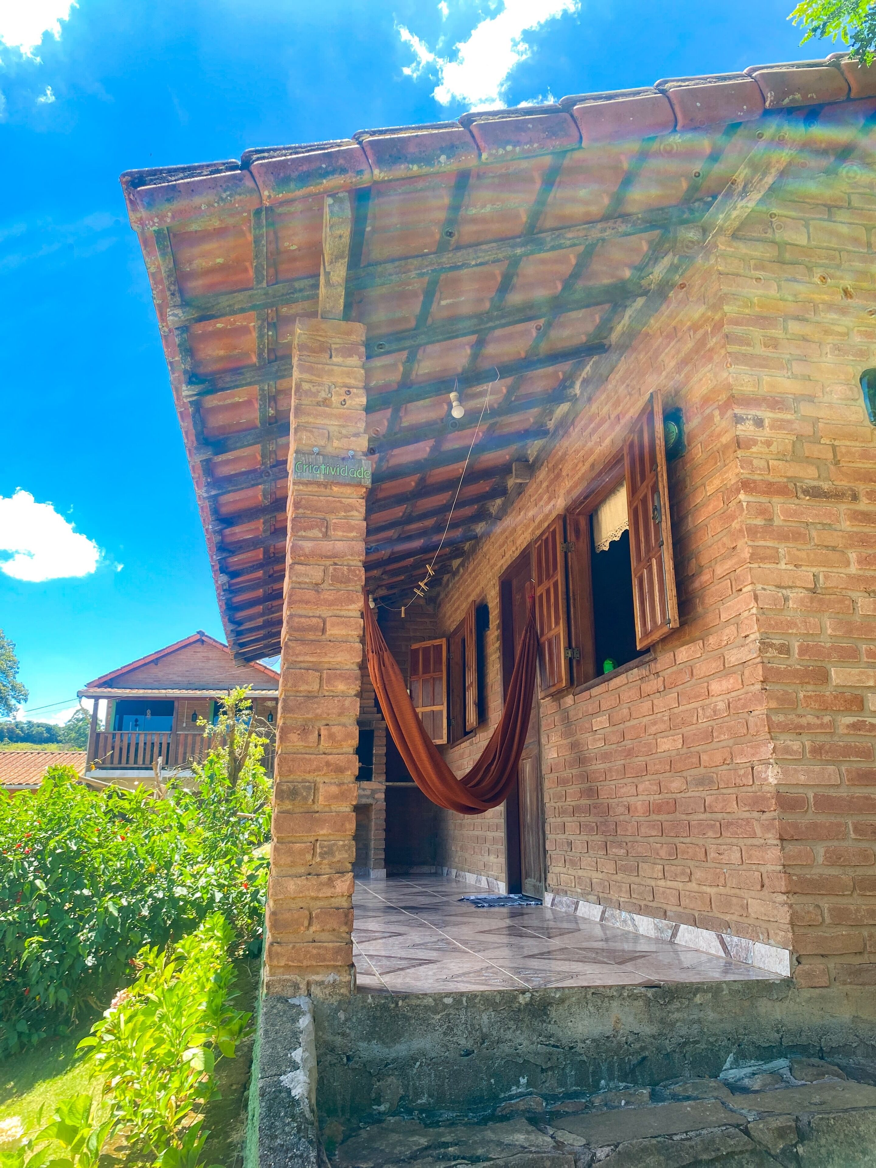 A brick house with a tiled porch and a hammock.