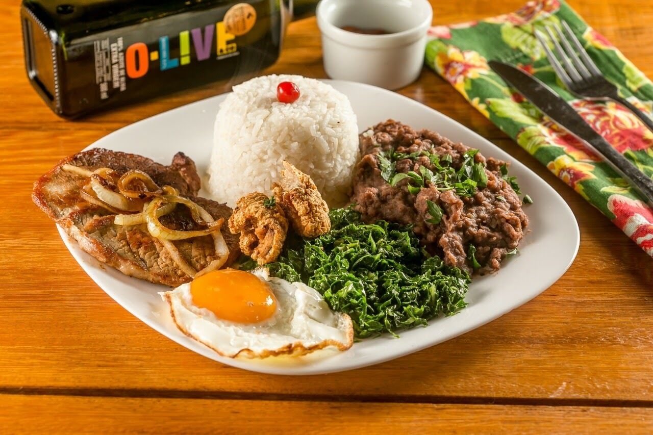 A plate of food with rice, beans, fried meat, and greens.
