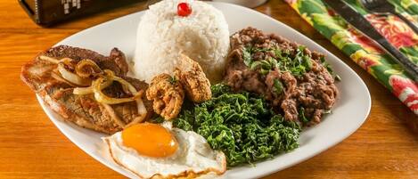A plate of food with rice, beans, fried meat, and greens.