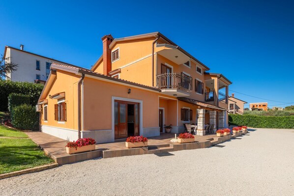 Une maison à deux étages avec un balcon, une porte d’entrée et une allée.