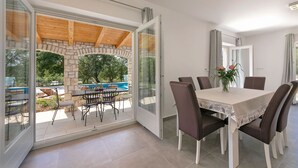 Un comedor con mesa y sillas, un arco de piedra y vistas a una piscina al aire libre.
