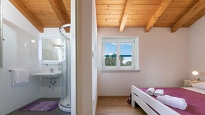Baño con ducha, lavamanos y ventana con vistas.