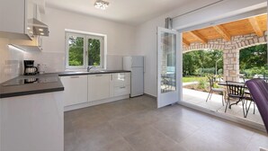 Una cocina moderna con armarios blancos, encimera negra y cafetera. Hay una ventana que ofrece luz natural y vistas al exterior.
