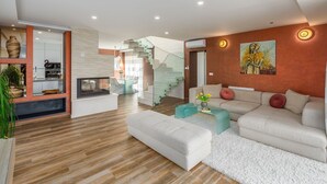 A modern living room with a fireplace, a staircase, and a dining area.