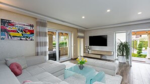 A modern living room with a sofa, a coffee table, and a TV mounted on the wall.