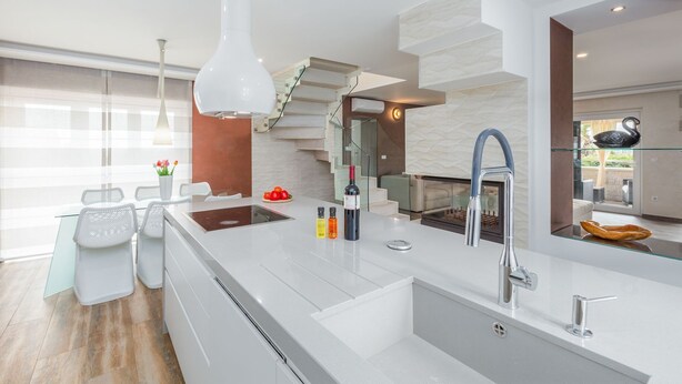 A modern kitchen with a central island, a built-in stove, and a sleek faucet.