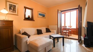 A living room with a sofa, a small table, a TV, and a dining area with chairs and a table. - Picturesque flat with pool, private terrace, washing machine, BBQ, loungers (Novigrad)