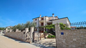 A two-story building with a stone wall and a metal gate. - Picturesque flat with pool, private terrace, washing machine, BBQ, loungers (Novigrad)