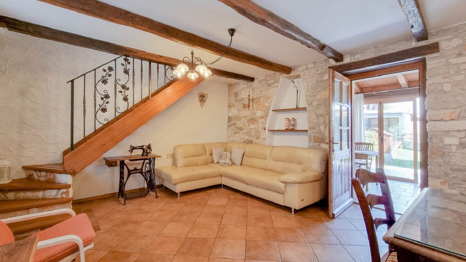 Ein gemütliches Wohnzimmer mit einer Holztreppe, einem beigefarbenen Sofa, einem Tisch und einer Kandelaber.