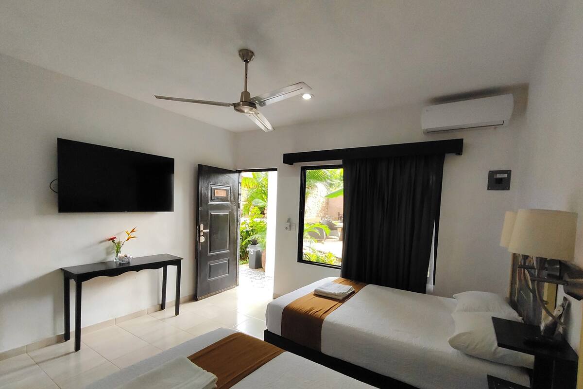A hotel room with a bed, a desk, a TV, and a ceiling fan.