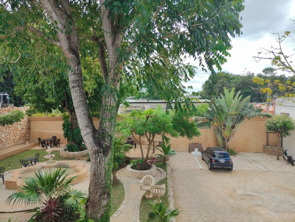 A courtyard with a fountain, seating area, and a parked car. - Casa Yaxche (Valladolid)
